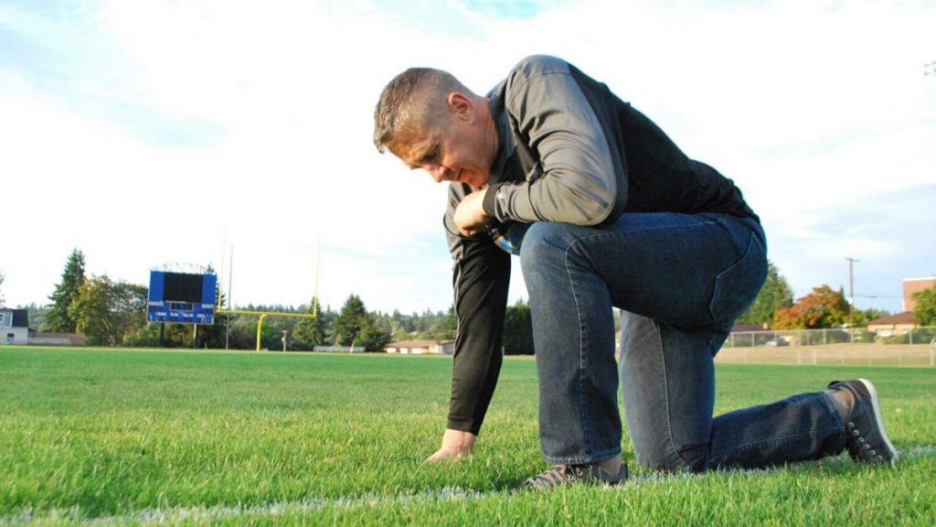 Coach Joe Kennedy prays on football field